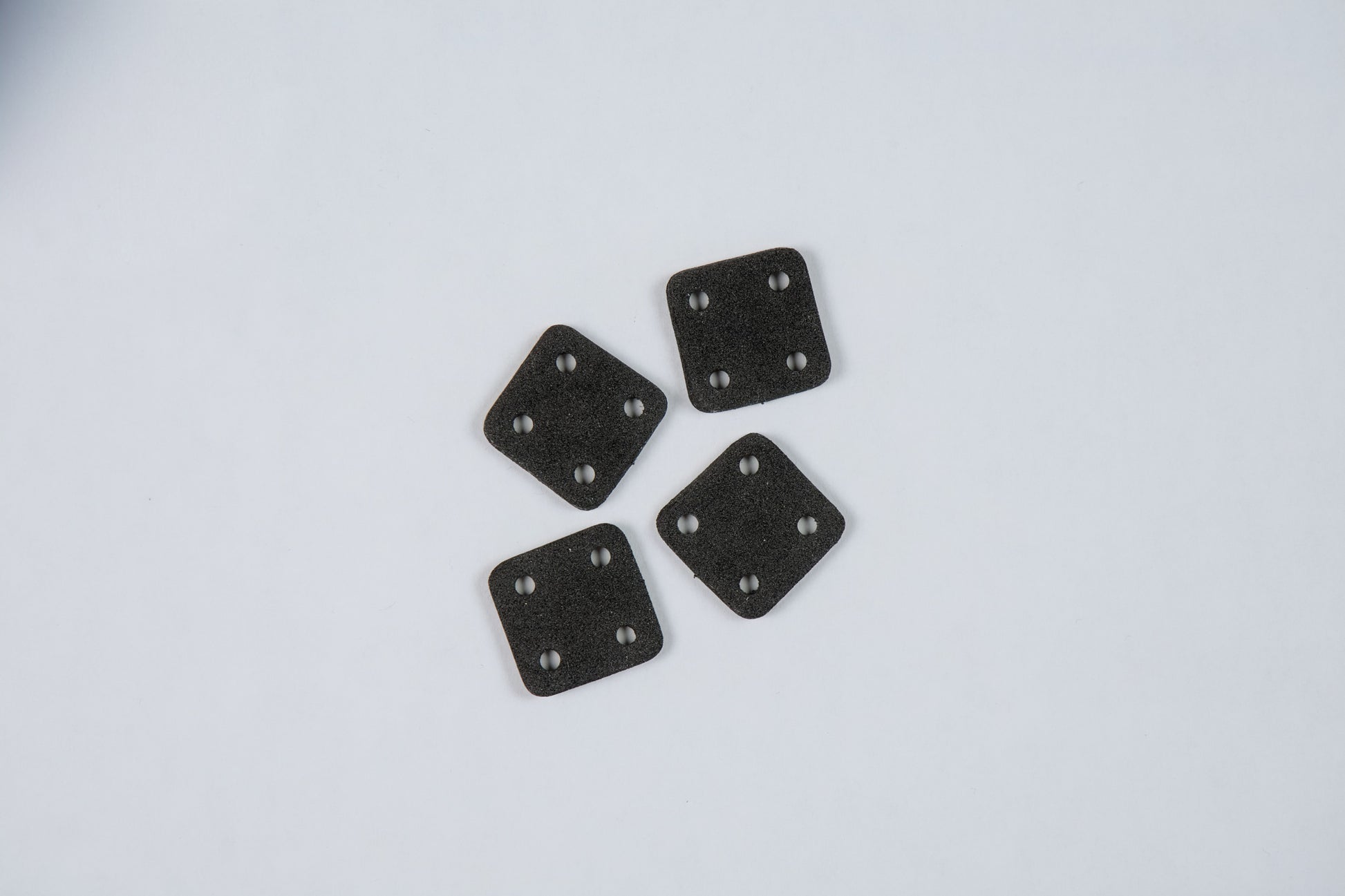 four black square anti-vibration foam pads on a white background